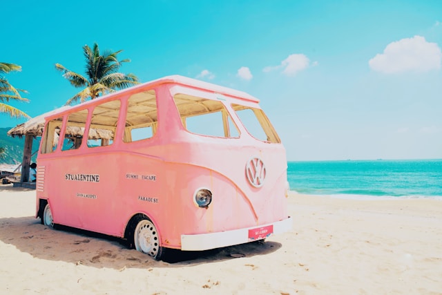 A pink empty bus on a beach